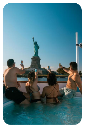 people on a hot tub boat in NYC looking at the statue of liberty