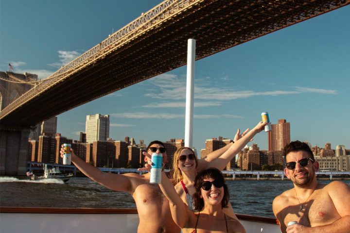 people posing in NYC hot tub boat in front of Brooklyn bridge