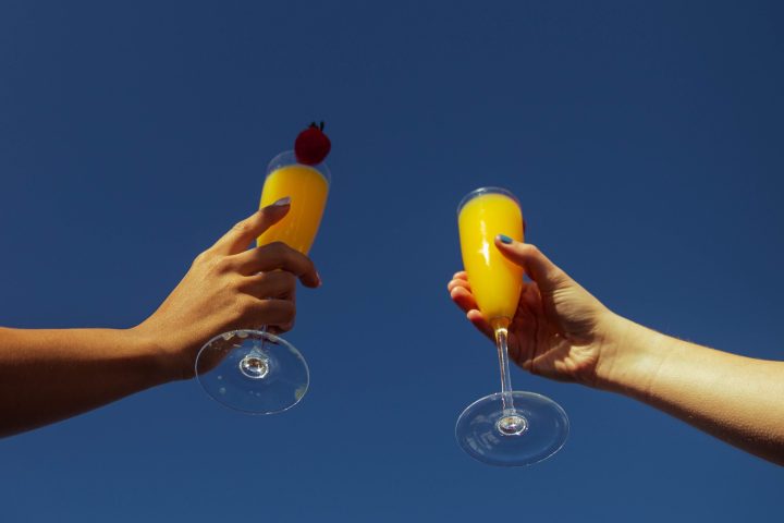 hands cheering mimosas on NYC Hot Tub Boat