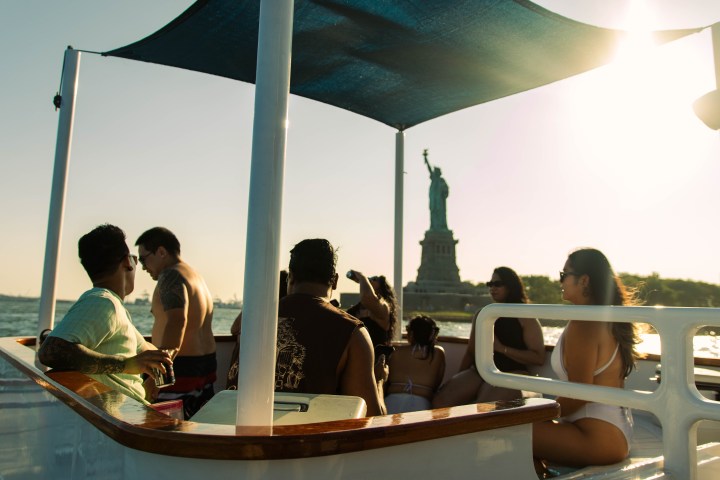 People on a boat near the Statue of Liberty during sunset.